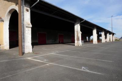 Salle de conférence vide avec des rangées de chaises noires, un écran de projection et des tables à l'avant.