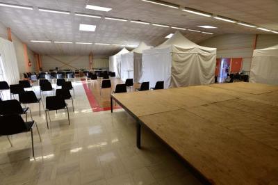 Salle de conférence vide avec des rangées de chaises noires, un écran de projection et des tables à l'avant.