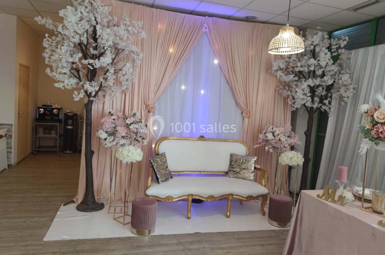 Décor élégant avec canapé doré, rideaux roses, arbres fleuris et éclairage doux dans une salle aménagée.