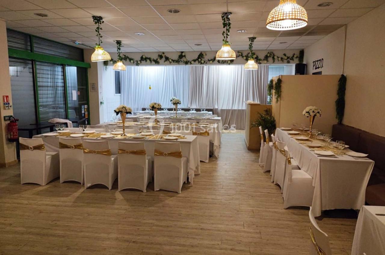 Salle de réception décorée avec des tables dressées, nappes blanches et ornements dorés, prête pour un événement.