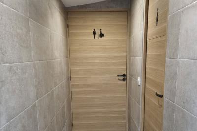 Toilettes modernes avec cuvette suspendue, carrelage gris, mosaïque dorée et accessoires noirs.