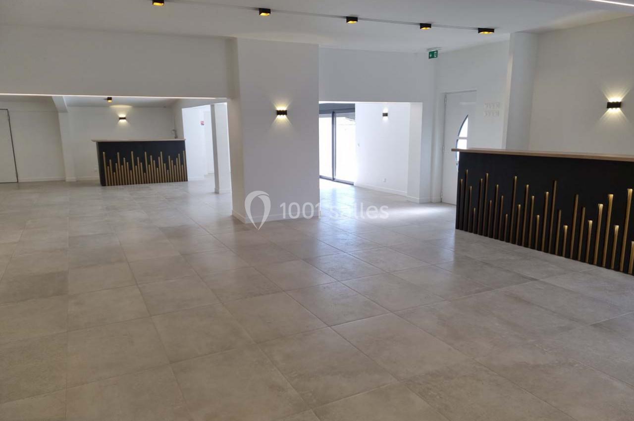 Salle spacieuse et lumineuse avec sol en carrelage clair, murs blancs et comptoirs décorés de motifs dorés.