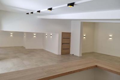 Toilettes modernes avec cuvette suspendue, carrelage gris, mosaïque dorée et accessoires noirs.