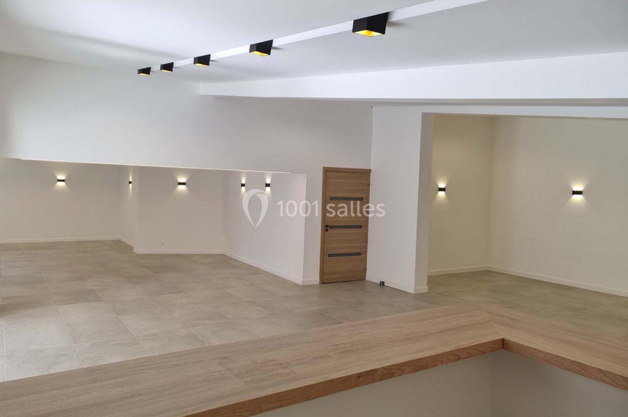 Intérieur moderne avec murs blancs, sol en carrelage beige, éclairage mural et plafond avec spots encastrés.