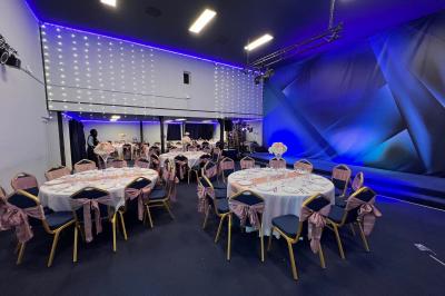 Salle sombre avec éclairage coloré, scène équipée de projecteurs, haut-parleurs et rideaux noirs en arrière-plan.