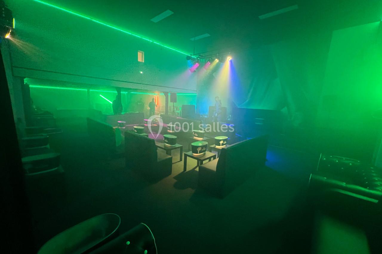 Salle sombre avec des fauteuils, éclairée par des lumières colorées et des projecteurs créant une ambiance festive.