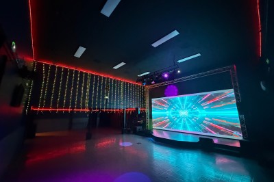 Salle de réception décorée avec des tables rondes, nappes bleues, chaises dorées et centres de table floraux blancs.