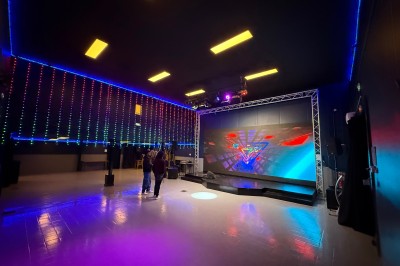 Salle de réception décorée avec des tables rondes, nappes bleues, chaises dorées et centres de table floraux blancs.