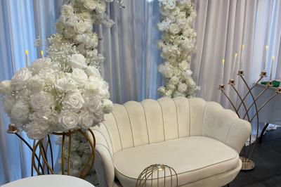 Salle de réception moderne avec tables dressées, sol en carrelage gris, éclairage suspendu et décor floral.