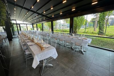 Salle de réception moderne avec tables dressées, sol en carrelage gris, éclairage suspendu et décor floral.