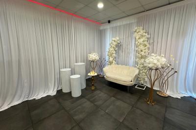 Salle de réception moderne avec tables dressées, sol en carrelage gris, éclairage suspendu et décor floral.