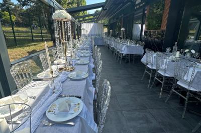 Salle de réception moderne avec tables dressées, sol en carrelage gris, éclairage suspendu et décor floral.