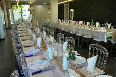 Salle de réception moderne avec tables dressées, sol en carrelage gris, éclairage suspendu et décor floral.