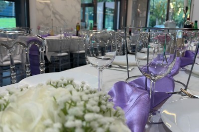 Salle de réception moderne avec tables dressées, sol en carrelage gris, éclairage suspendu et décor floral.