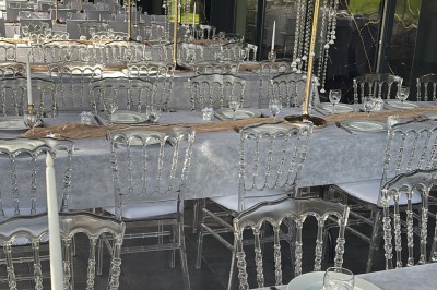 Salle de réception moderne avec tables dressées, sol en carrelage gris, éclairage suspendu et décor floral.