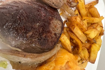 Assiette contenant un steak grillé, une purée de pommes de terre, une salade verte et une sauce servie dans un ramequin.