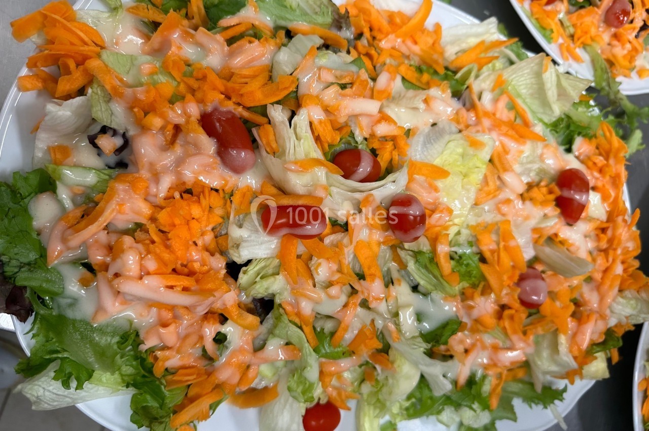 Assiette de salade composée avec laitue, carottes râpées, tomates cerises et sauce rose.