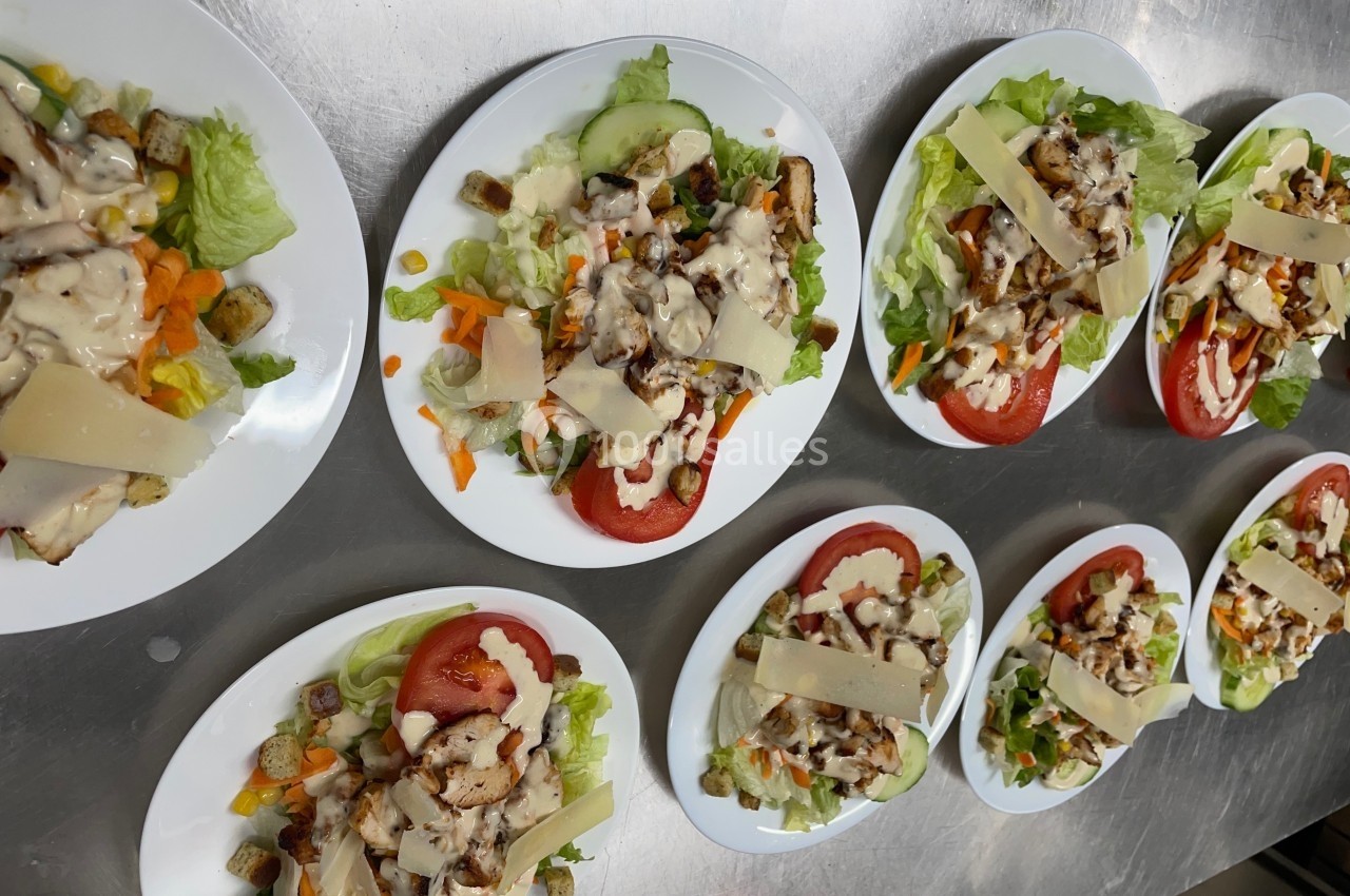 Assiettes de salades composées avec laitue, tomates, poulet, croûtons, carottes râpées, fromage et sauce blanche.
