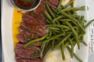 Assiette contenant un steak grillé, une purée de pommes de terre, une salade verte et une sauce servie dans un ramequin.