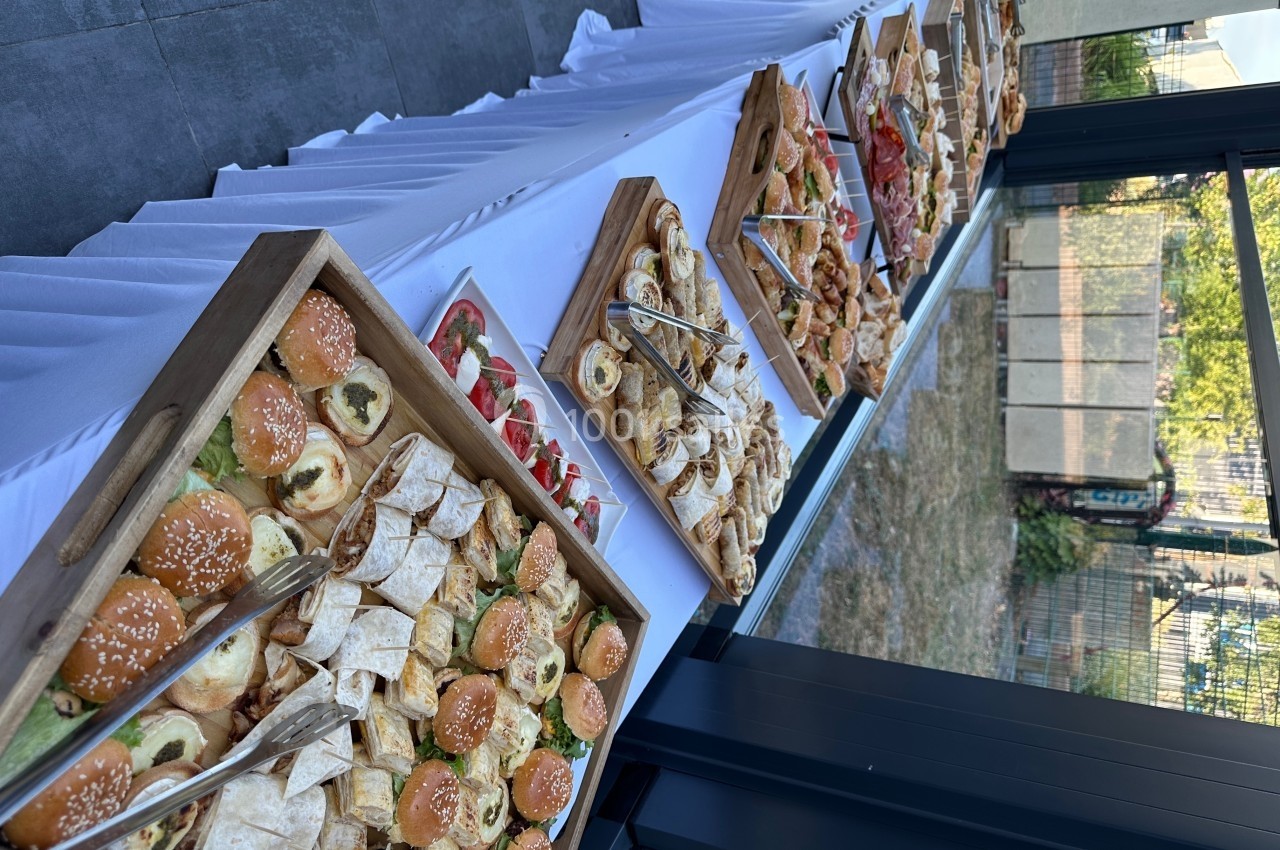 Buffet de viennoiseries et amuse-bouches variés disposés sur une longue table blanche près d'une baie vitrée.