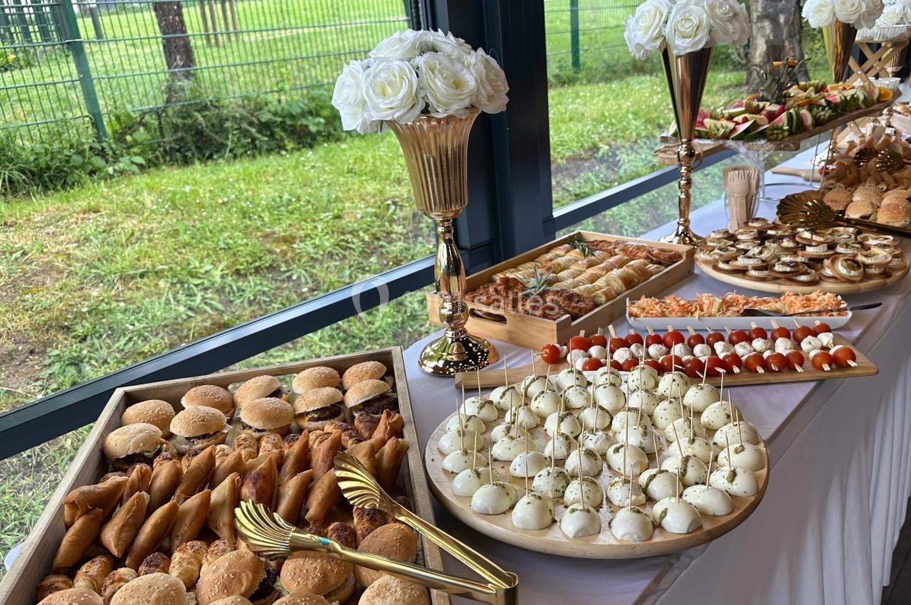 Buffet varié avec mini-burgers, brochettes, feuilletés et autres amuse-bouches disposés sur une table élégante.