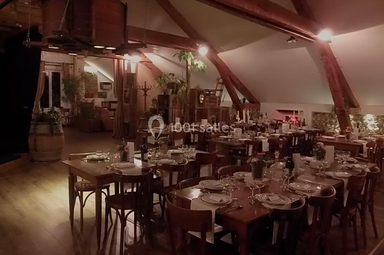 Salle de restaurant rustique avec tables en bois dressées, poutres apparentes et décoration chaleureuse.