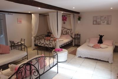 Chambre lumineuse avec lits en bois, bureau, armoire, décorations végétales et vue sur un jardin par la fenêtre.