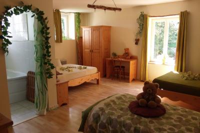 Chambre lumineuse avec lits en bois, bureau, armoire, décorations végétales et vue sur un jardin par la fenêtre.