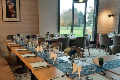 Paysage de golf avec pelouses verdoyantes, reliefs ondulés et maisons en arrière-plan sous un ciel dégagé.