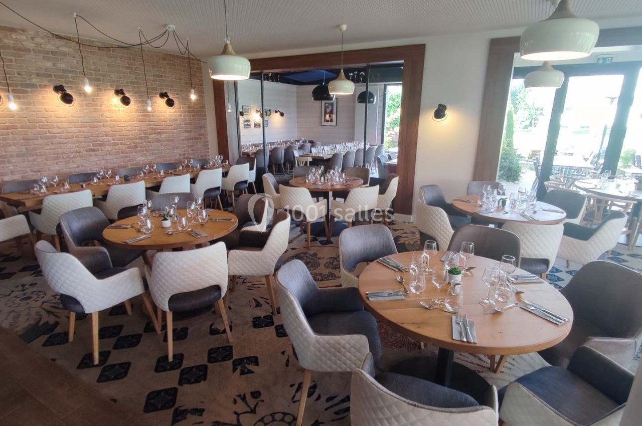 Salle de restaurant lumineuse avec tables rondes dressées, chaises rembourrées et décor moderne aux tons neutres.