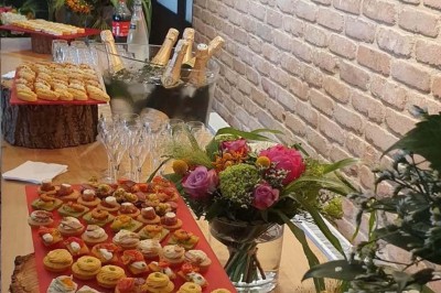 Plateau d'éclairs salés disposés sur une table avec des bouteilles de champagne dans un seau de glace en arrière-plan.
