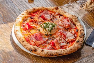 Assiette de pâtes rigatoni à la truffe avec une tuile de fromage, servie sur une table en bois.