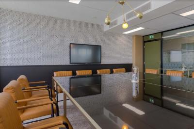 Salle de réunion moderne avec table en marbre, chaises bleues, écran mural et cloison vitrée décorative.