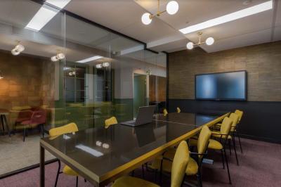 Salle de réunion moderne avec table en marbre, chaises bleues, écran mural et cloison vitrée décorative.