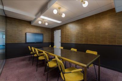 Salle de réunion moderne avec table en marbre, chaises bleues, écran mural et cloison vitrée décorative.