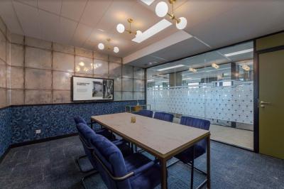Salle de réunion moderne avec table en marbre, chaises bleues, écran mural et cloison vitrée décorative.