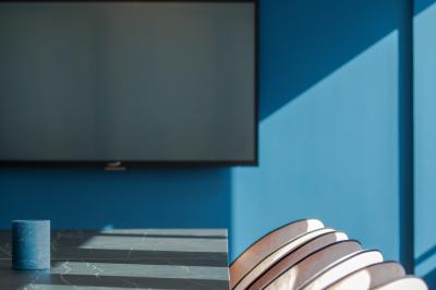 Salle de réunion moderne avec table en marbre, chaises bleues, écran mural et cloison vitrée décorative.