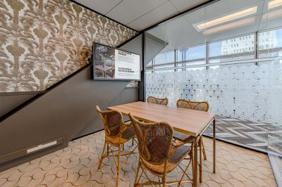 Deux personnes discutent dans une salle de réunion moderne avec écran mural et mobilier haut.