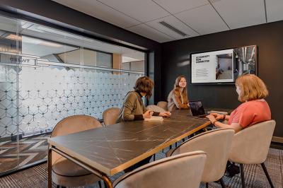 Deux personnes discutent dans une salle de réunion moderne avec écran mural et mobilier haut.