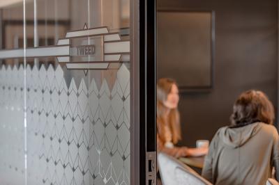 Deux personnes discutent dans une salle de réunion moderne avec écran mural et mobilier haut.