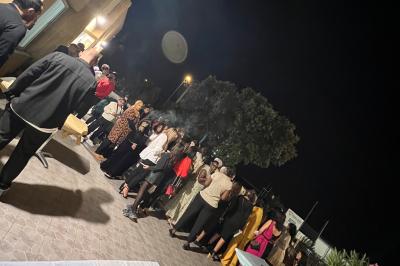 Salle de réception décorée pour un mariage, avec tables dressées, fleurs blanches et rouges, et arche florale en arrière…