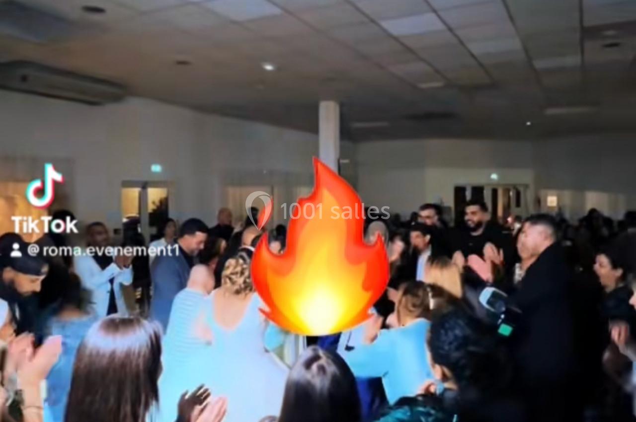 Un groupe de personnes dans une salle éclairée, applaudissant autour d'une animation de flamme ajoutée numériquement.