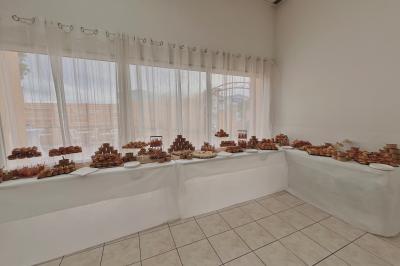 Salle de réception décorée pour un mariage, avec tables dressées, fleurs blanches et rouges, et arche florale en arrière…