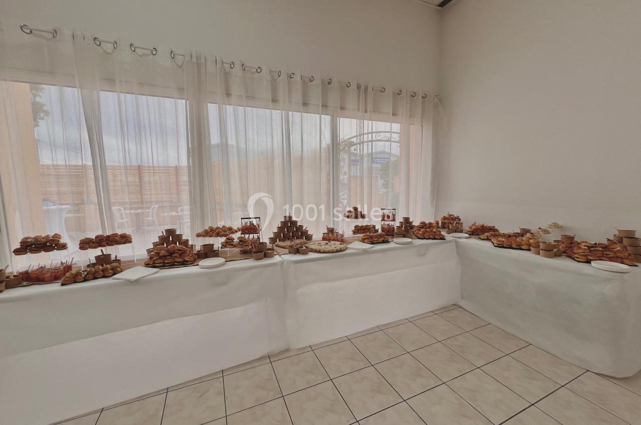 Table garnie de pâtisseries variées disposées sur des présentoirs dans une salle lumineuse avec de grandes fenêtres.