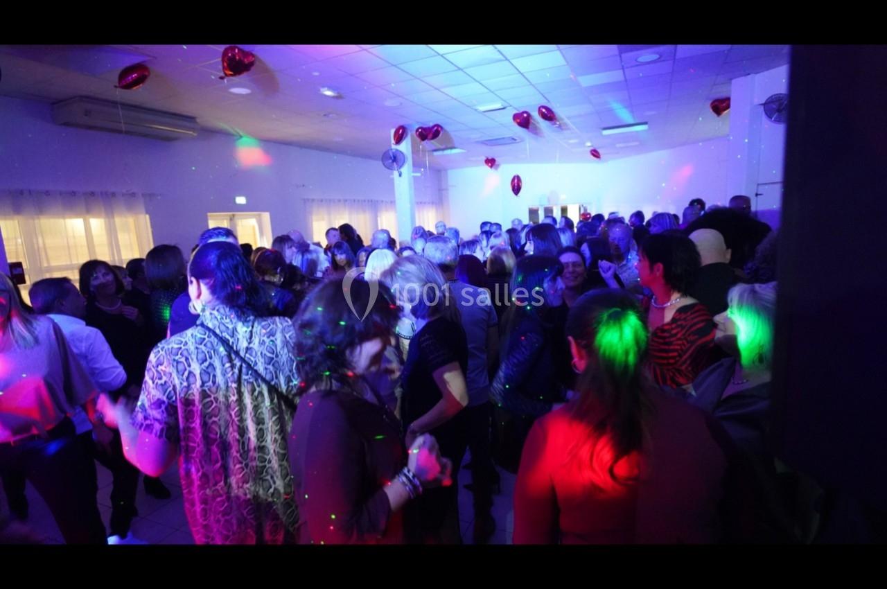 Groupe de personnes dans une salle sombre, éclairée par des lumières colorées, lors d'un événement festif.