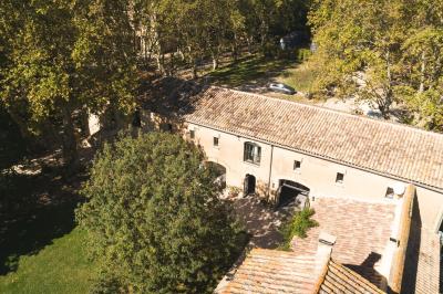 Chambre lumineuse avec lit double, commode en bois, portant à vêtements, télévision et poutre apparente au plafond.