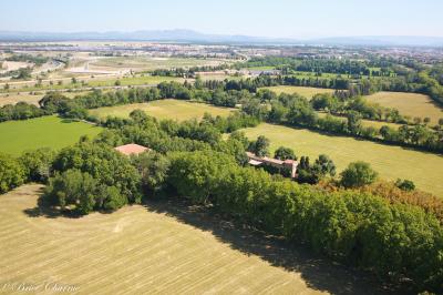 Chambre lumineuse avec lit double, commode en bois, portant à vêtements, télévision et poutre apparente au plafond.