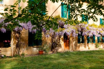 Chambre lumineuse avec lit double, commode en bois, portant à vêtements, télévision et poutre apparente au plafond.