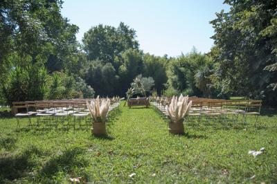 Chambre lumineuse avec lit double, commode en bois, portant à vêtements, télévision et poutre apparente au plafond.