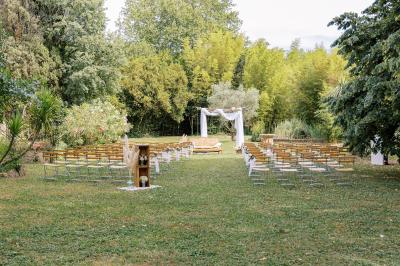 Chambre lumineuse avec lit double, commode en bois, portant à vêtements, télévision et poutre apparente au plafond.